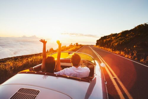 Glückliches Paar fährt auf einer Landstraße in den Sonnenuntergang