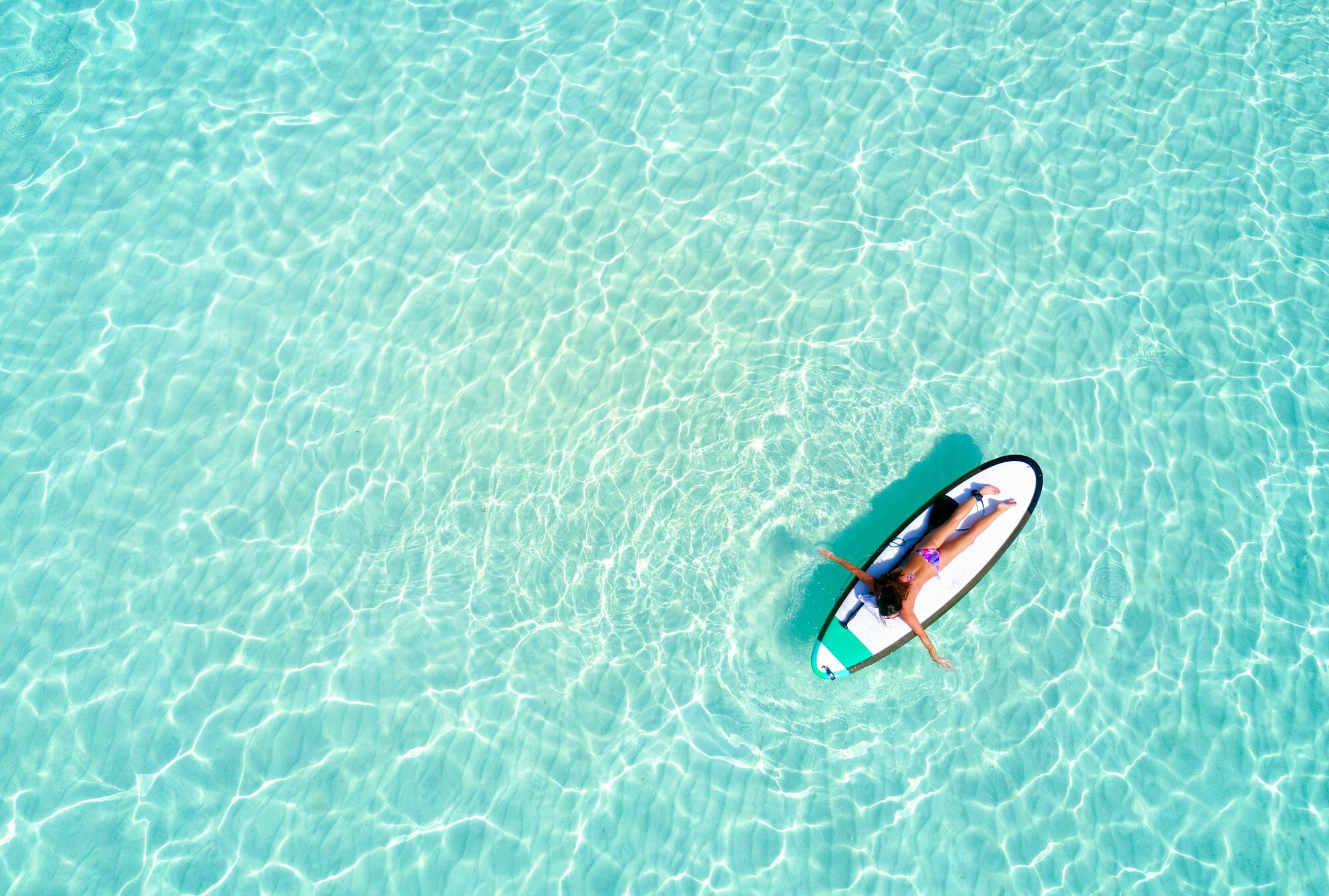 Luftaufnahme einer Frau auf einem Surfbrett im Meer